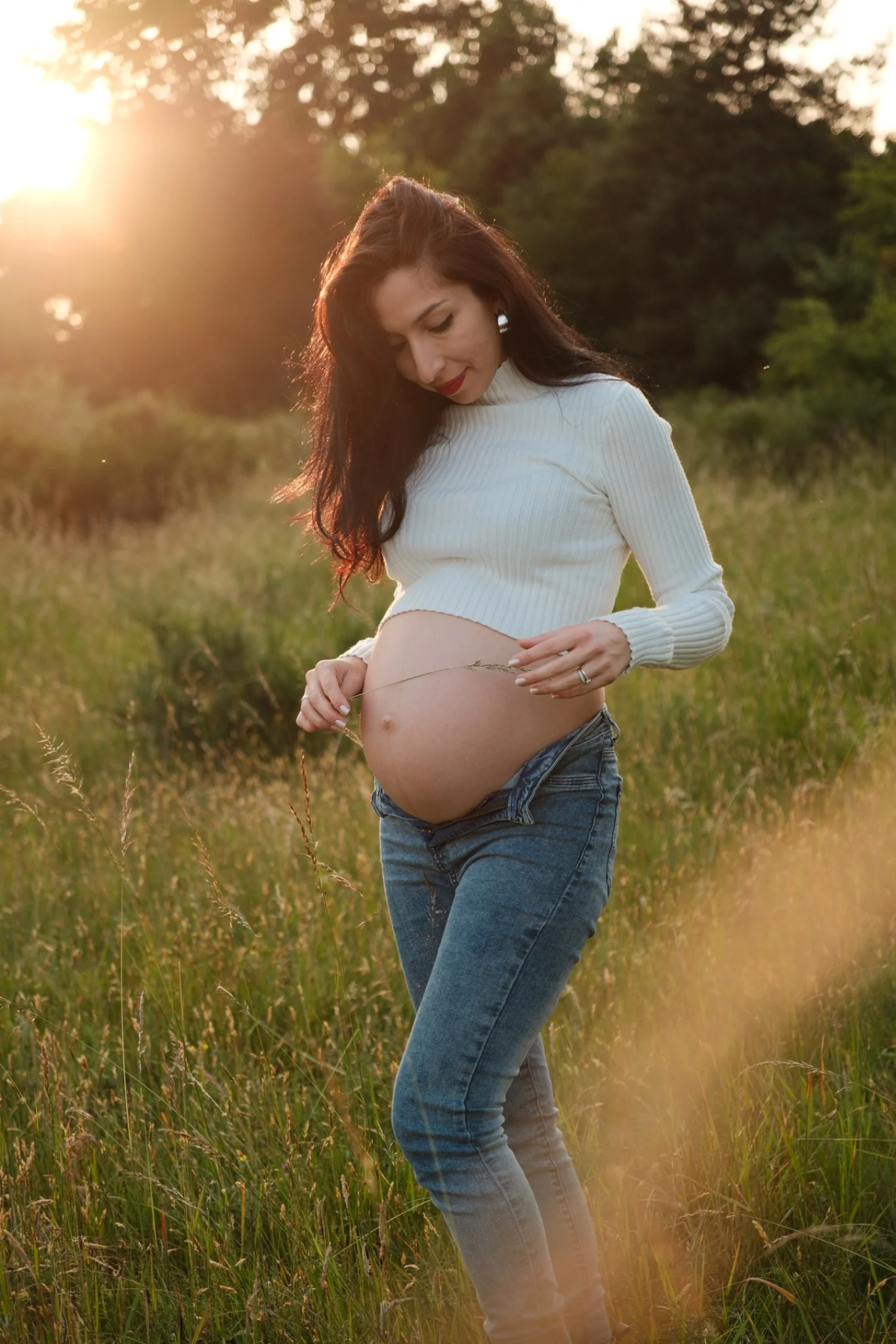 Schwangere mit Babybauch im Licht des Sonnenuntergangs