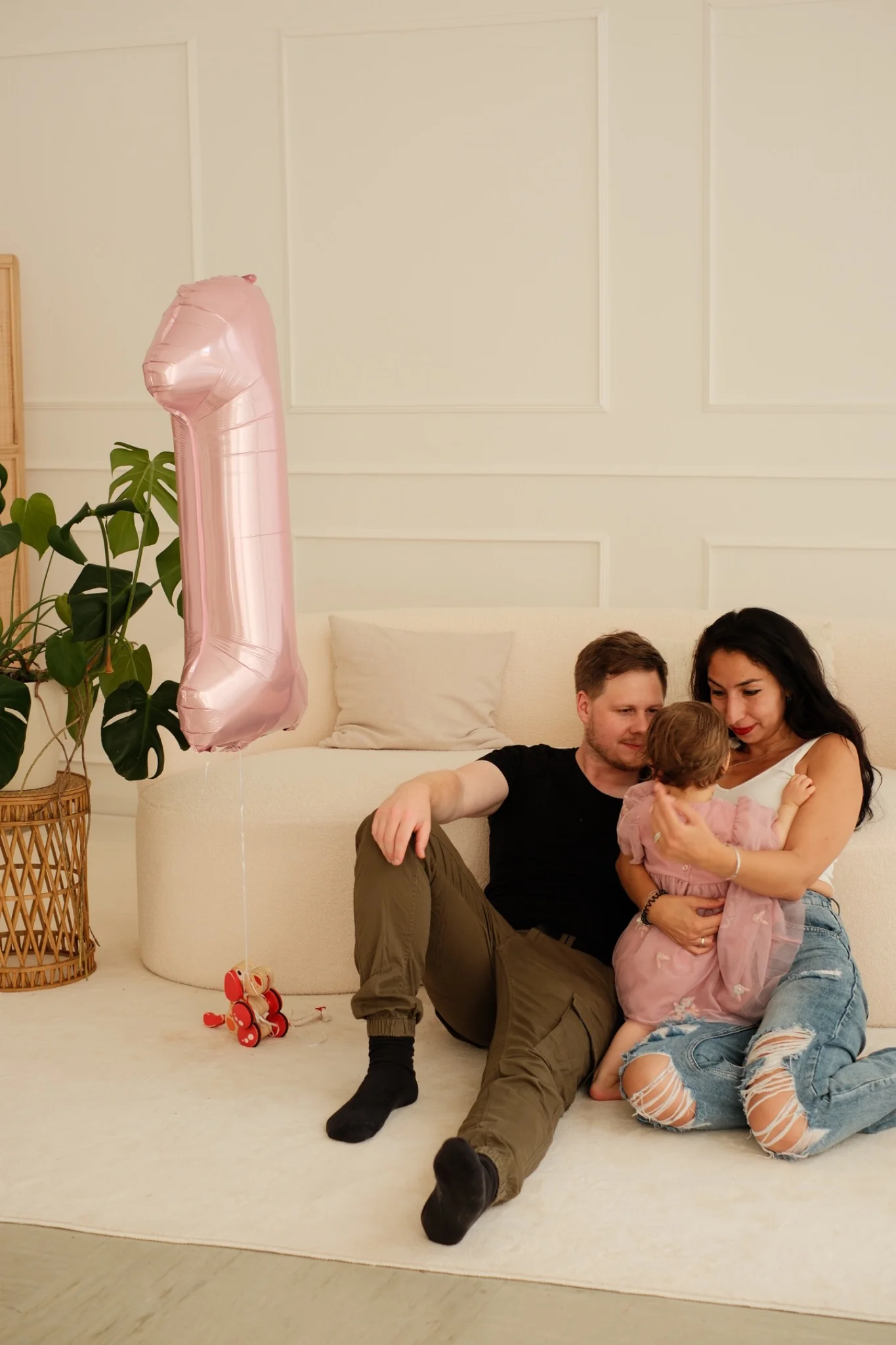Familie sitzt zusammen auf dem Sofa, daneben ein Ballon zur Eins